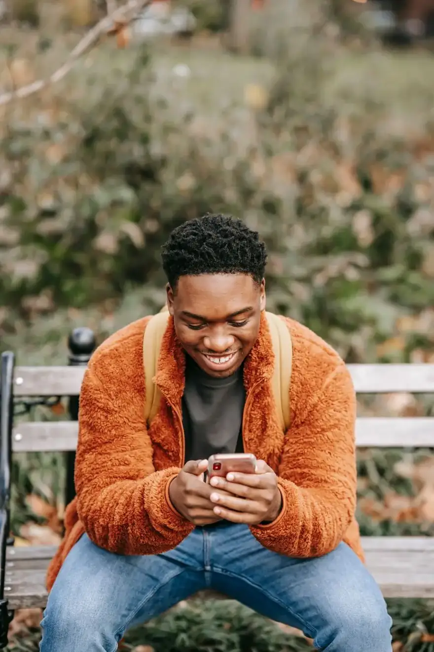 A young man smiling as he checks his phone